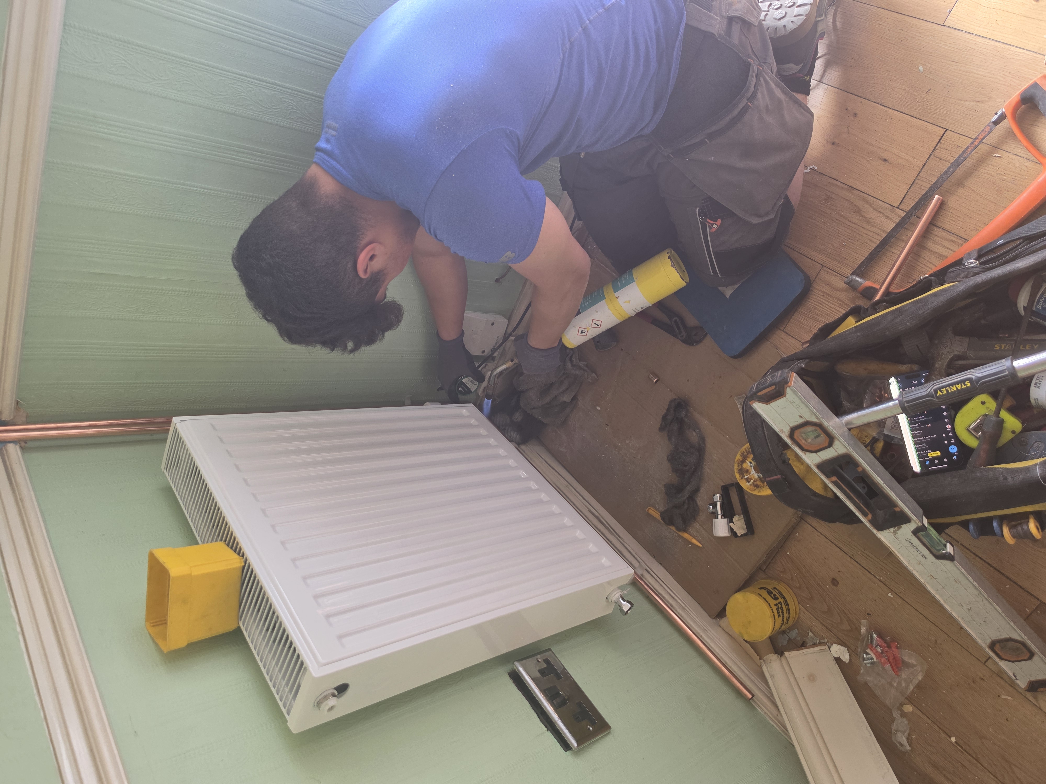 Heating engineer fitting radiator during full heating system installation